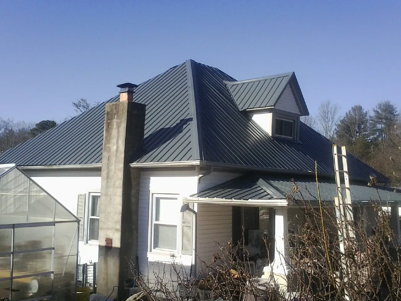 Dark blue standing seam metal roof on a white farmhouse with dormer — Slate & Tile Roof Repair by Roofing Brothers in Enon Valley