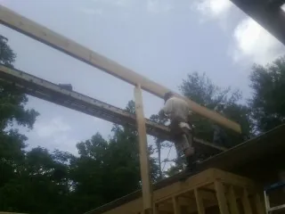 Carpenter setting a ridge beam over a new addition frame — Ice Dam Removal by Roofing Brothers in Enon Valley