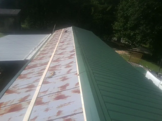 Old rusted panels beside newly installed green metal roofing — Wind Damage Roof Repair by Roofing Brothers in Enon Valley