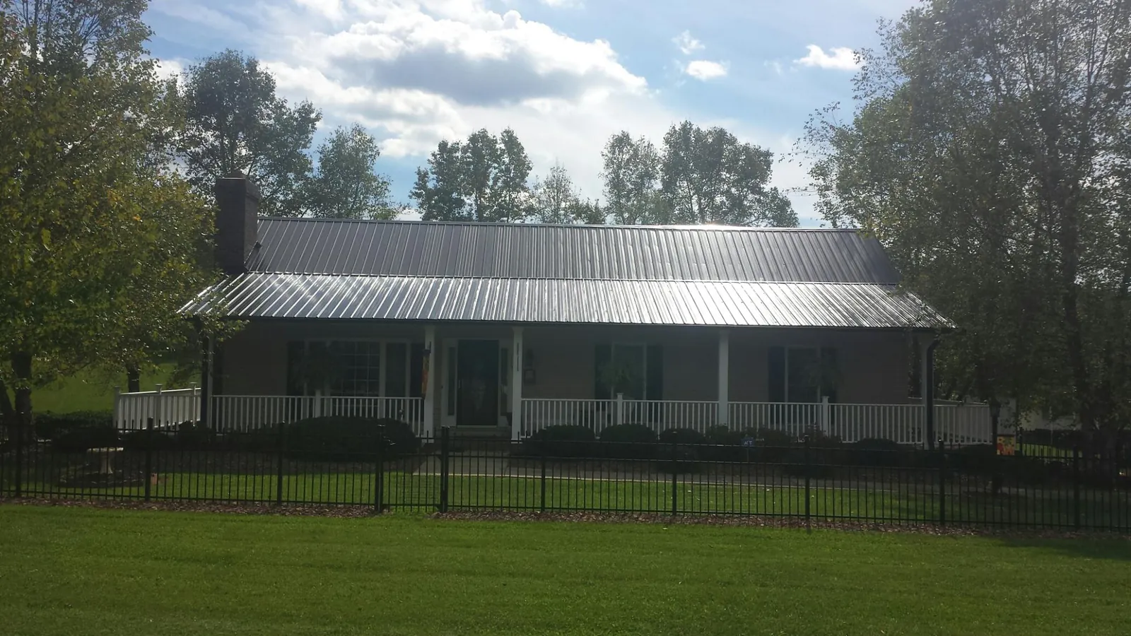 Gray metal roof on a brick ranch with a full width front porch — Gutter Guard Installation work by our crew in Enon Valley