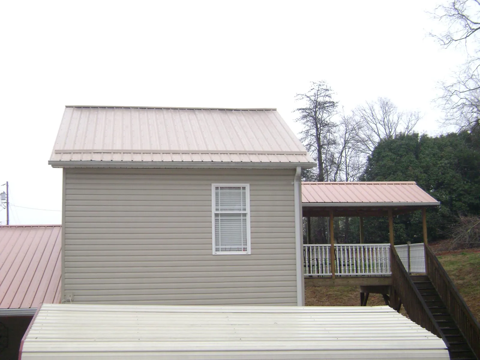 Tan metal roofs on a two story addition and attached porch, from a Roof Replacement job in Enon Valley