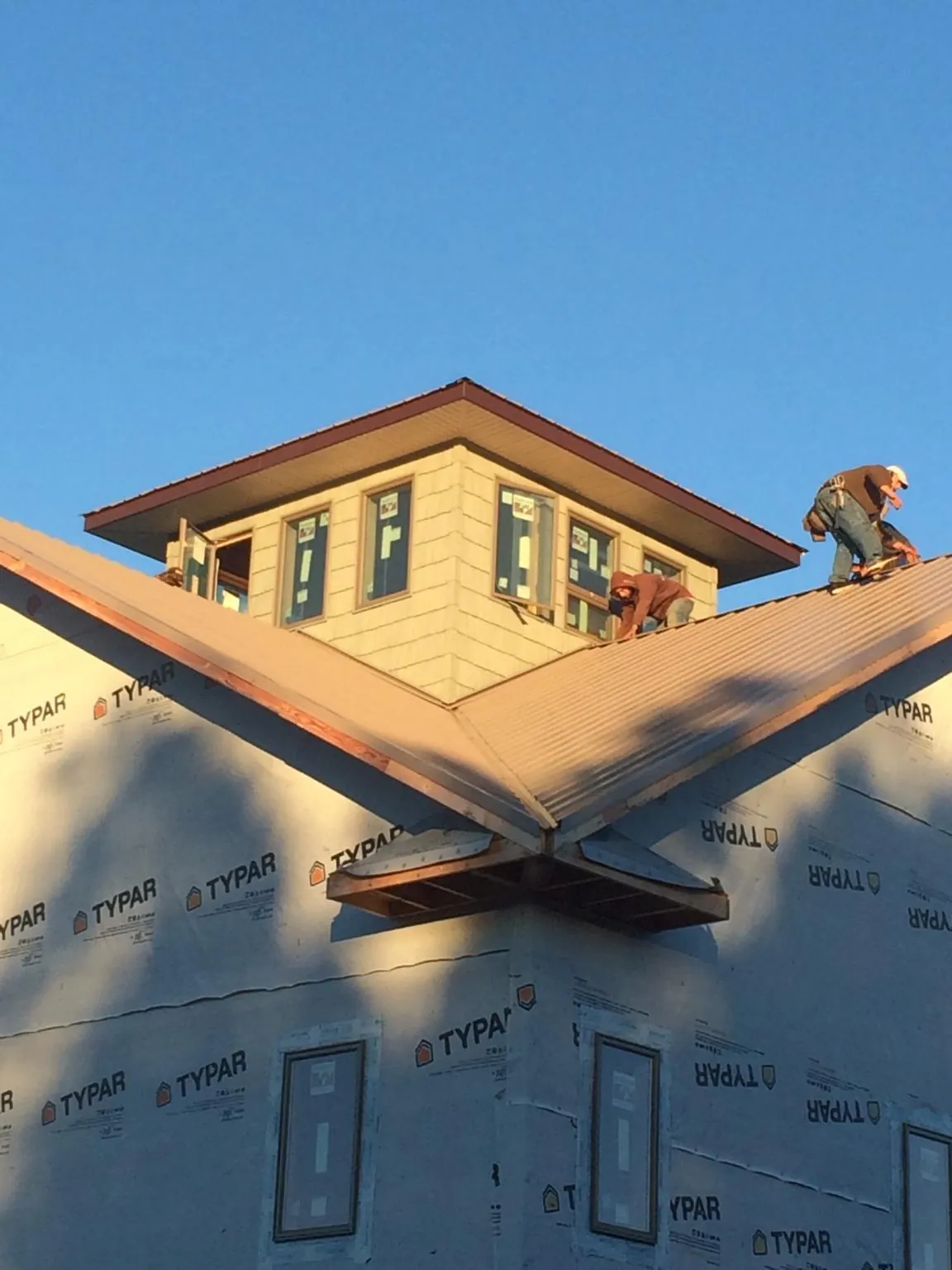 Roofers working around a rooftop cupola on a new metal roof at sunset — Roof Waterproofing in Enon Valley by Roofing Brothers